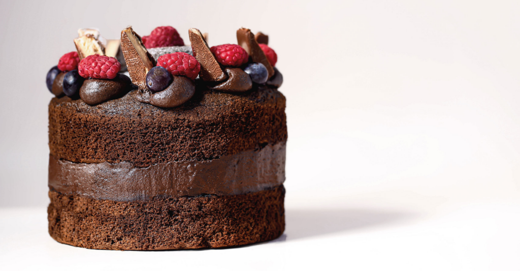 A dark chocolate celebration cake topped with berries and chocolate