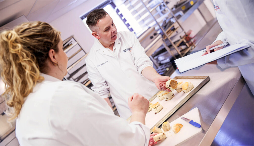 Bakers in the bakery assessing and discussing bakes